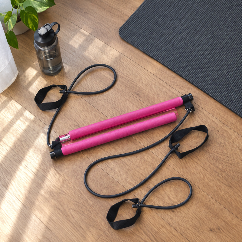 Barre de fitness FlexBar posée sur un parquet à côté d'un tapis et d'une gourde